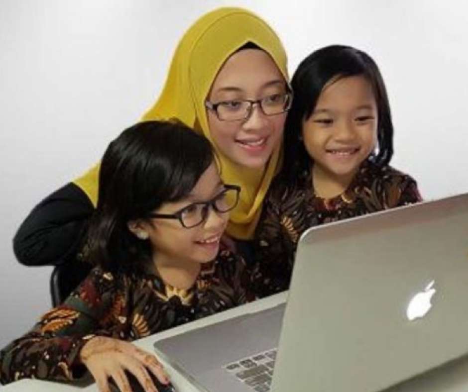 Tutor and two primary school students smiling during an online lesson on a laptop